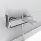 Chrome-Badearmatur von Ideal Standard mit einem Wasserhahn und zwei temperaturgeregelten Bedienelementen, angebracht an einer weißen Wand, mit einem Schlauch und Wandhalter.